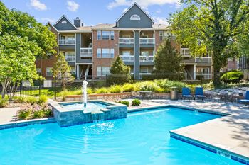 A beautiful swimming pool with a fountain and lush landscaping at Stonebriar Apartments in Overland Park, KS.